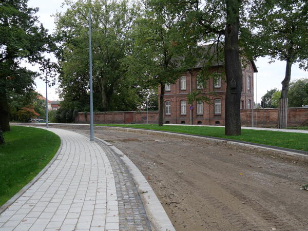 Das Foto zeigt die Hafenstraße mit bereits fertig gestelltem Fußweg aber noch fehlender Fahrbahndecke mit Blick auf das Garnisonsmuseum.