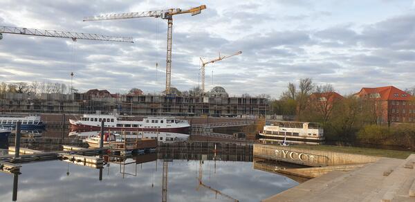 Das Bild zeigt das Hafenbecken in Celle mit einem Flusskreuzfahrtschiff. Im Hintergrund sind die Kräne der Baustelle für die Wohnbebauung am Hafenbecken zu sehen.