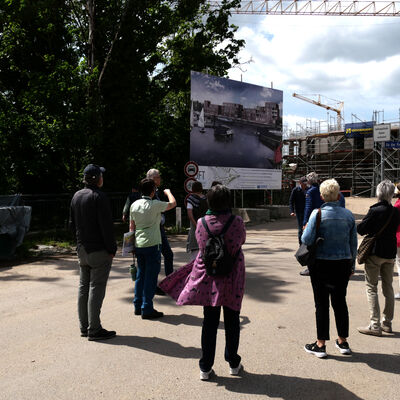 Das Foto zeigt eine Gruppe bei einer Führung auf der Allerinsel an der Station, wo die in Umsetzung befindliche Wohnbebauung erläutert wird.