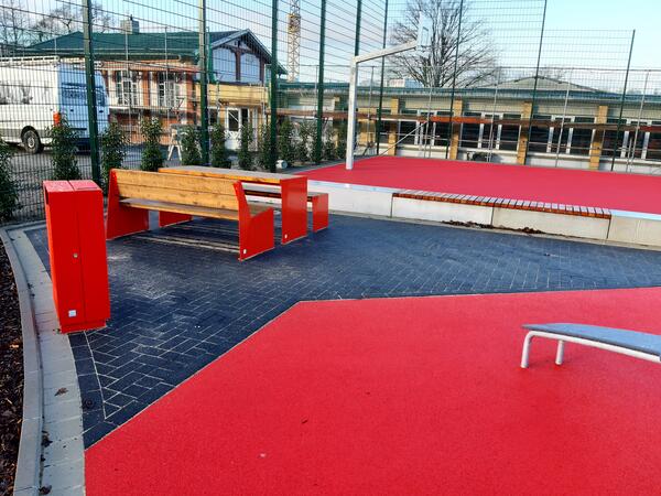 Blick auf den Basketballplatz im Allerauenpark in Celle. Im Vordergrund Sitzbnke mit Tisch.