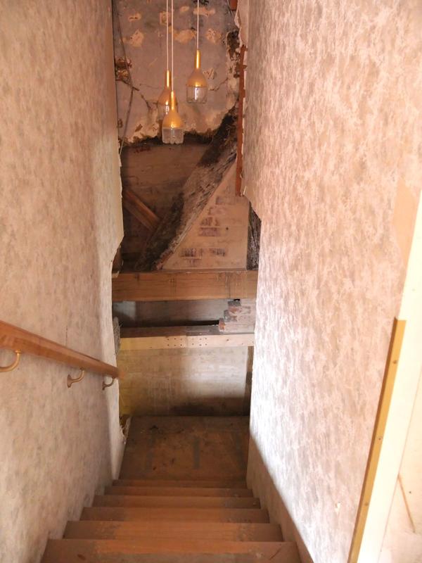 In einem Treppenaufgang ist die Wand geöffnet um Schäden hinter der Tapete entdecken zu können.
