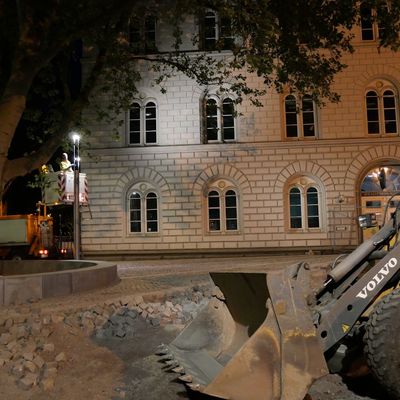 Ein Bagger steht bei Dunkelheit auf der ruhenden Baustelle vor dem Gebäude der Stadtbibliothek.